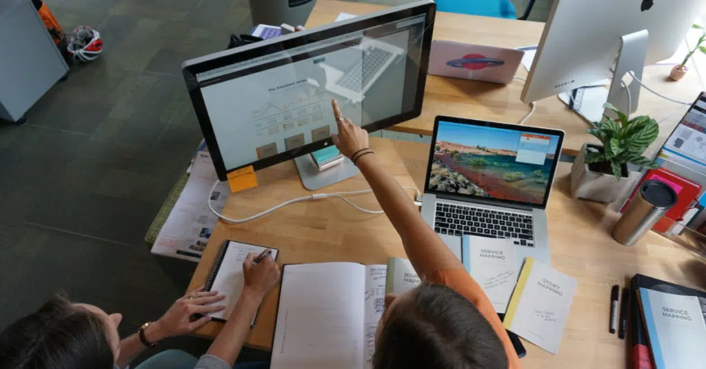 UX versus UI Design: Why It Matters for Your Software Product 1 Two employees discussing UX vs UI design and why it matters for software products.